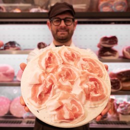 Pancetta Piacentina affettata in mano banco salumi
