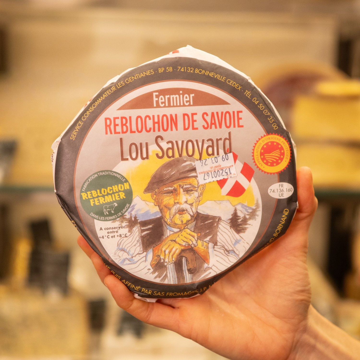 forma incartata di reblochon aop di savoia in mano